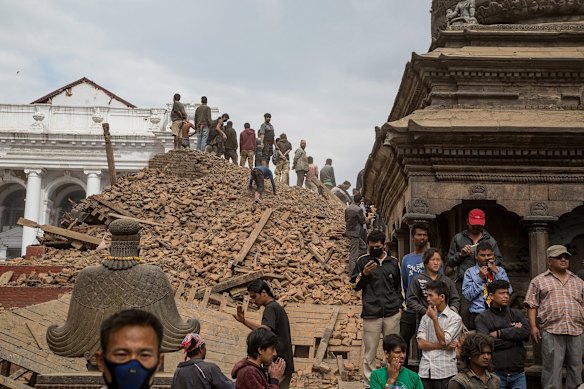 Emergency workers and bystanders clear debris while searching for survivors under a collapsed temple in Basantapur Durbar Square following an earthquake in Kathmandu, Nepal.
