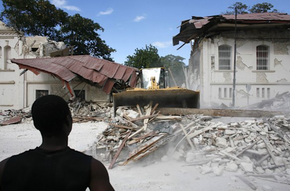A resident looks at debris being removed from the national palace.