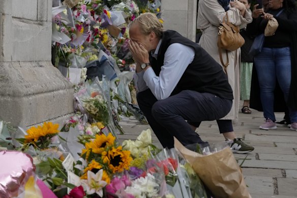 A mourner is overcome with emotion as he pays his respect at the gates of Buckingham Palace in London, Friday, Sept. 9, 2022.