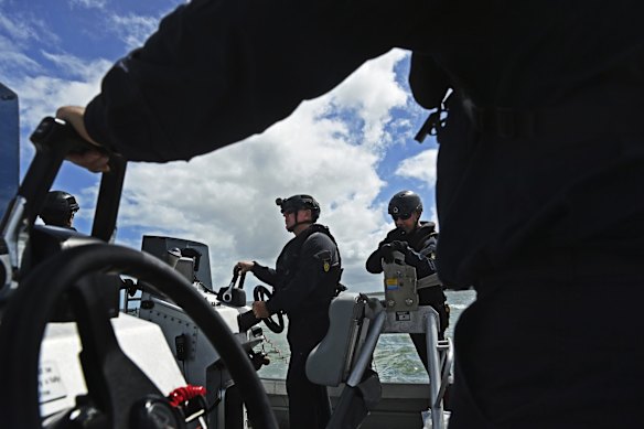 Australian Border Force (ABF) marine tactical officers Jason Meyers (left) and Ed Harris (right) on a tender boat patrolling off Australia's Saibai Island near the PNG coastline (in background).