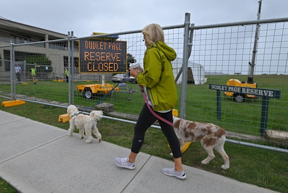 A woman walks her dog past Dudley Page Reserve, which has been closed as a precaution against COVID-19, on New Years Eve.
