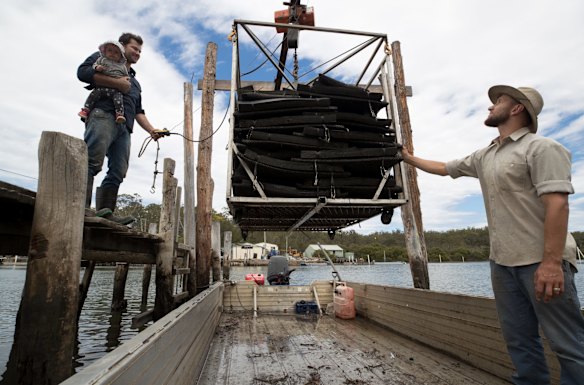 Oyster farmer, Ewan McAsh with his eight-month-old daughter, Ivy and his brother-in-law, Jason Finlay, bring in oysters to their shed on the Clyde River. 