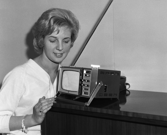 Janice admires the woman’s-cosmetic-case-sized portable television. 