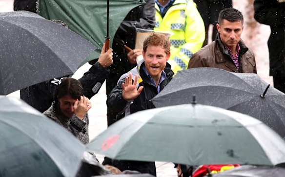 Britain's Prince Harry, center, waves as he meets well-wishers during a short walk in the rain on June 7, 2017 in Sydney, Australia.