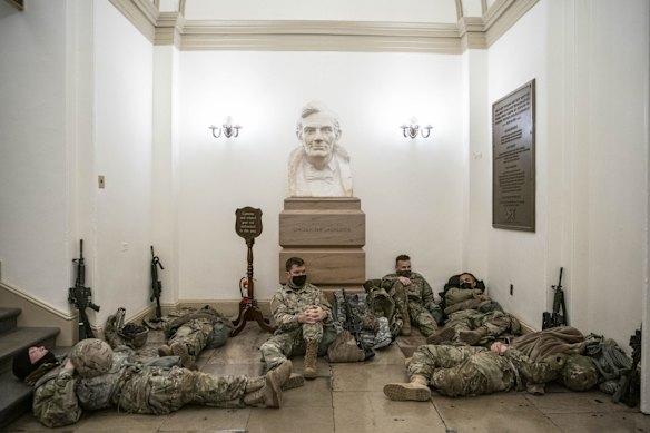 Members of the National Guard rest in a hallway of the US Capitol building underneath a bust of former US president Abraham Lincoln on Wednesday, January 13, 2021. The US House was preparing to vote on a history-making second impeachment of Donald Trump,