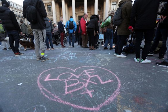 A message which says Love BXL is written on the ground as people leave tributes at the Place de la Bourse.