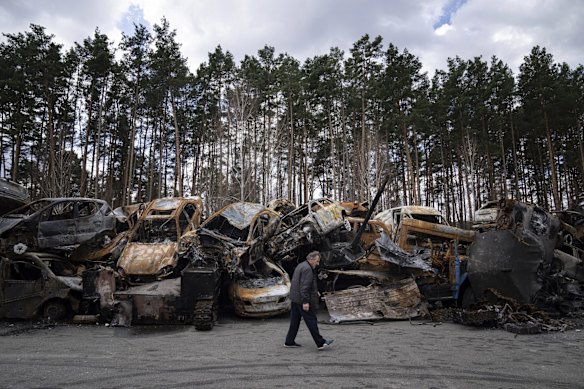 A man walks past burned armed vehicles and cars on the outskirts of Kyiv.