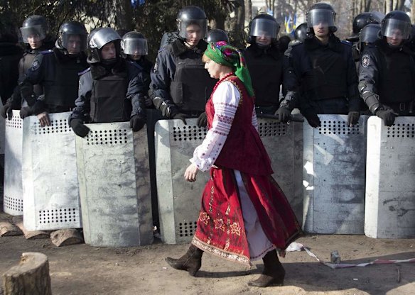 A woman dressed in Ukrainian national clothes walks past a line of Interior Ministry members in Kiev, February 18, 2014. Ukrainian riot police advanced on the heart of 12-week-old protests against President Viktor Yanukovich on Tuesday and security forces set a deadline to end disturbances after at least five protesters were reported killed in a day of clashes.