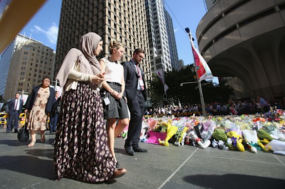 Mourners walk together after placing flowers at Martin Place on Tuesday. 