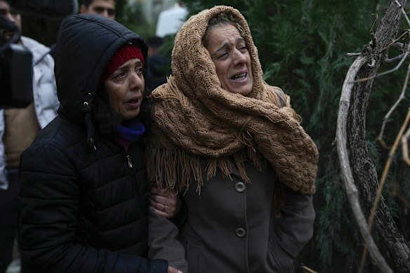 Women cry as they watch emergency teams search for people in the rubble of a destroyed building in Adana, Turkey.