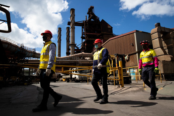 BlueScope employees (from left) Chris Page, Michael Reay, and Craig Nealon walk past part of the blast furnace operating at Port Kembla.