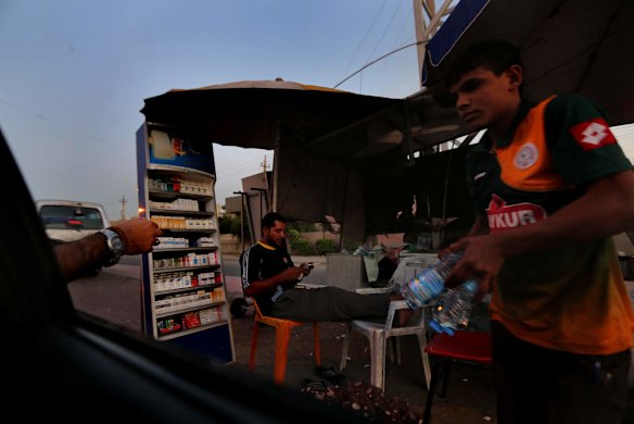 An Iraqi boy and man sell drinks and cigarettes from their roadside stall in Baghdad, Iraq.