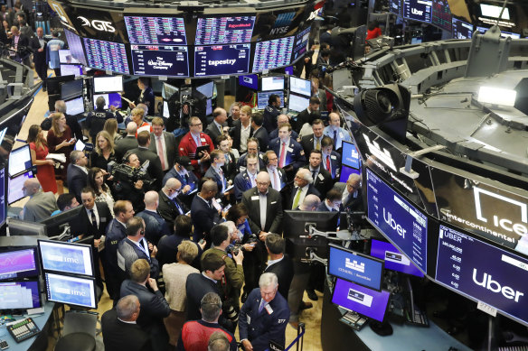 Stock traders gather around the post where Uber shares began trading. 