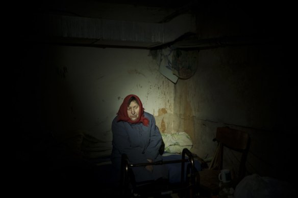 An elderly woman hides in a basement for shelter, with no electricity in Irpin.
