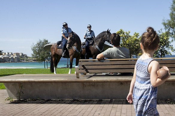 Police on patrol question a man why he is out at Bondi Beach. 
