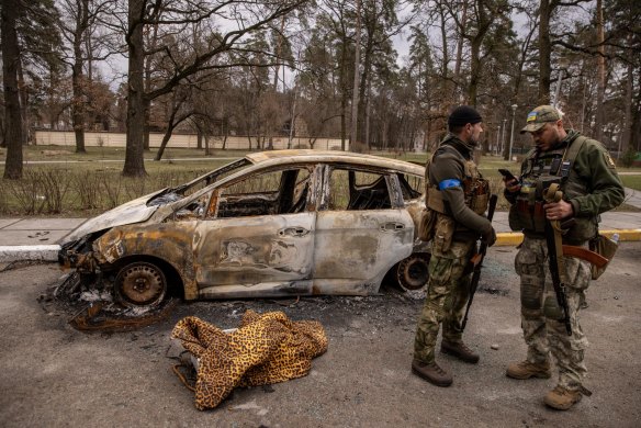 Members of the Ukrainian military stand by a destroyed vehicle in Bucha, Ukraine, on April 6.