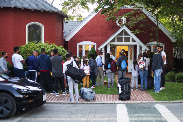 Göçmenler eşyalarıyla birlikte Martha's Vineyard'daki bir kilisenin dışında toplanıyor.