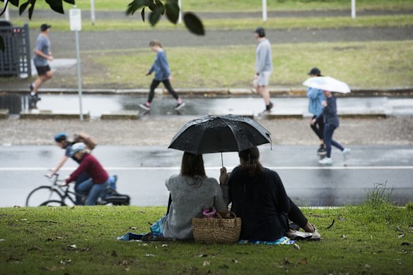 Picnics are packed up as the rain begins to fall at Centennial Park, as some restrictions ease.