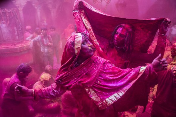 Hindu devotees dance as others play with colour in the village of Barsana, India.
