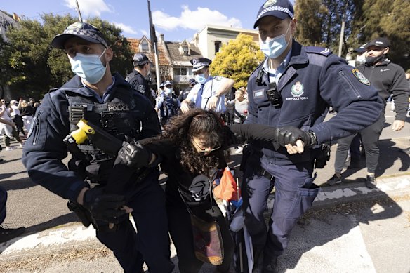 Police arrest a woman on Broadway during a large Anti-lockdown protest.