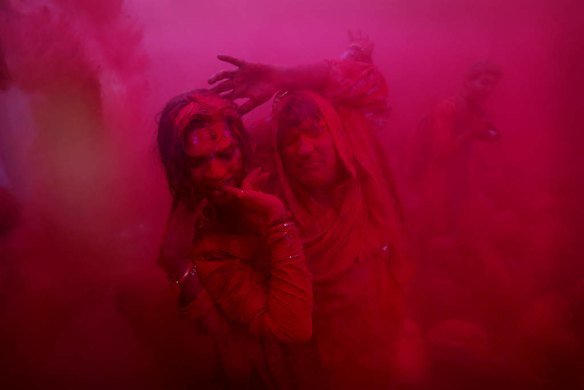 People dance as coloured powder is thrown in Barsana, India.