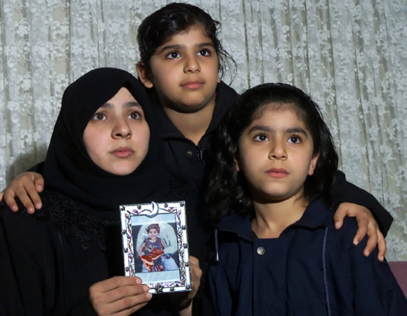 SIEV X survivors Najah Zubaydi, with her daughters Anfal, 9, (centre) and Naba, 8, (right) and a photo of her 18-month-old son Karrar, who  drowned.