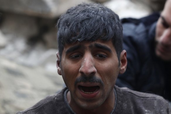 A man reacts as Syrian Civil Defence workers and security forces search through the wreckage of collapsed buildings, in Aleppo, Syria.