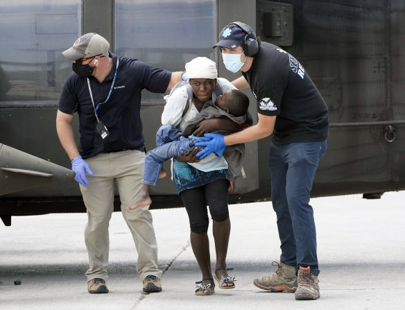 Rescue workers help an injured woman and a boy from a helicopter. 