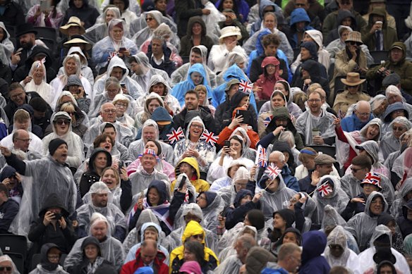 Crowds brave the rain opposite Buckingham Palace.