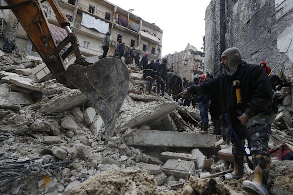 Syrian civil defence workers and security forces search through the wreckage of collapsed buildings, in Aleppo, Syria.