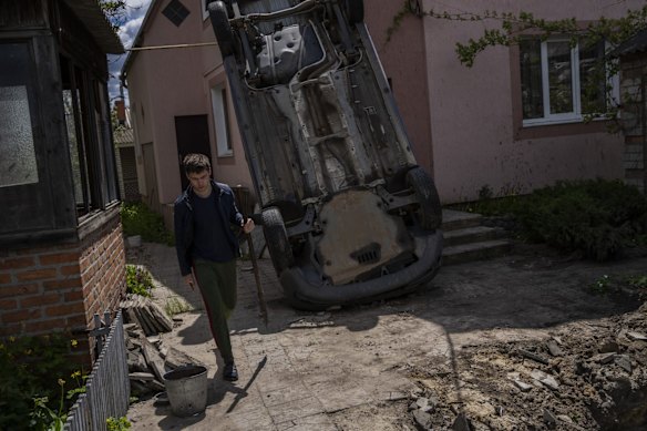 A resident carries a shovel to clear rubble from his house, which was damaged by shelling in Kharkiv.