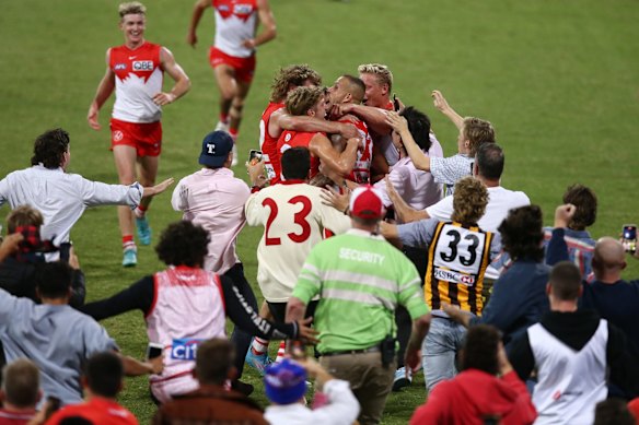 Lance Franklin celebrates with teammates as the crowd run onto the field.