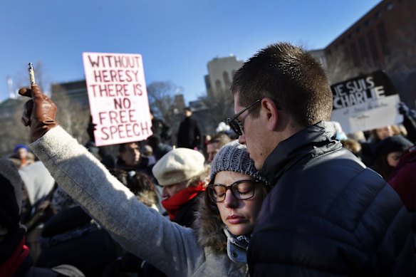 Laura Dugu, originally of Toulouse, France, symbolically holds a pen in the air as several hundred people gather in solidarity with victims of two terrorist attacks in Paris, one at the office of weekly newspaper Charlie Hebdo and another at a kosher market, in New York's Washington Square Park, Saturday, Jan. 10, 2015.