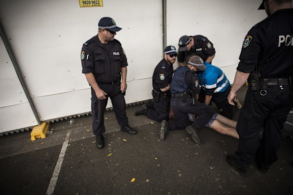Police detain an event-goer in Sydney Olympic Park.