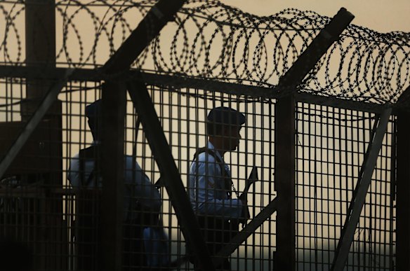 Indonesian police and security guard the fence line of Ngurah Rai International airport during the transfer of Bali Nine duo Myuran Sukumaran and Andrew Chan.