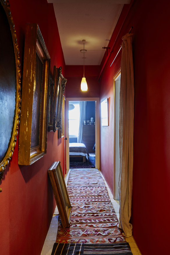The hallway walls are painted a luscious tangerine and lined with portraiture featuring ornate gilt frames. Kilim runners from Turkey cover painted floorboards.
