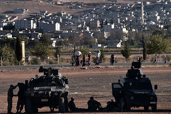 Refugees from the Syrian town of Ain al-Arab, known as Kobane by the Kurds, walk with their belongings after crossing the Turkish border with Syria near the city of Sanliurfa on October 4, 2014. Photo by AFP