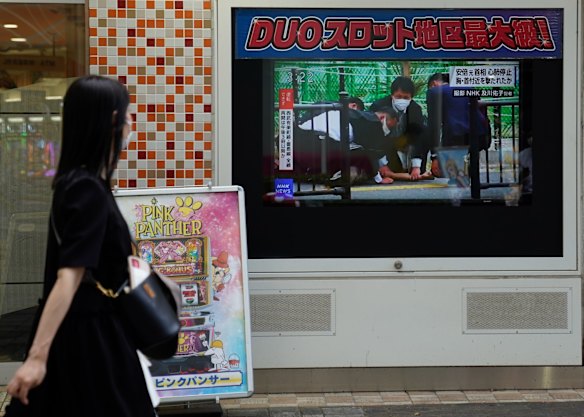 A woman looks at a screen broadcasting the news of the shooting. A suspect was apprehended and taken into custody, as Abe was rushed to a hospital via helicopter.