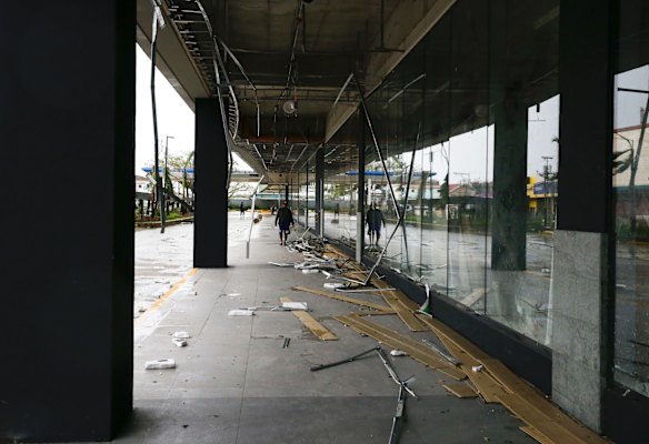 Workers clean up debris outside a mall that got partially damaged by strong winds.