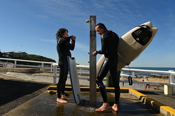 JR (left) and a friend rinse off after a surf near the ocean baths at Newcastle, as temperatures rise during lockdown.