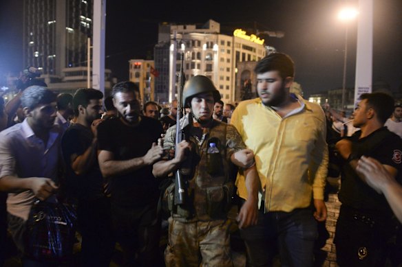A Turkish soldier, arrested by civilians, is walked to be handed to police officers, in Istanbul's Taksim square, early Saturday.