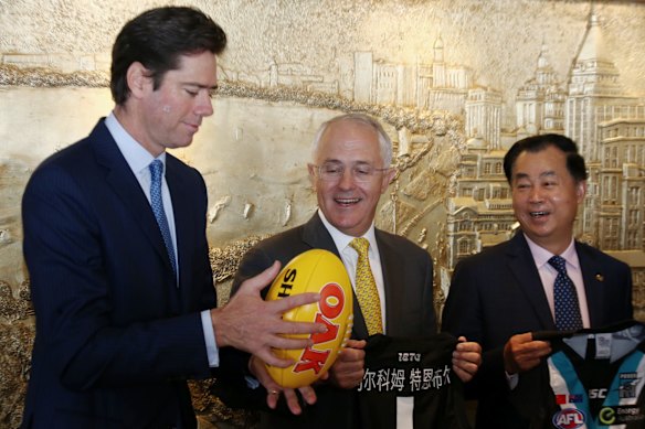 Prime Minister Malcolm Turnbull watches AFL CEO Gillon McLachlan catch a Sherrin during a signing ceremony with Guojie Gui from Shanghai CHEN real estate in Shanghai China on Thursday 14 April 2016. Port Adelaide will play a round in Shanghai in 2017.