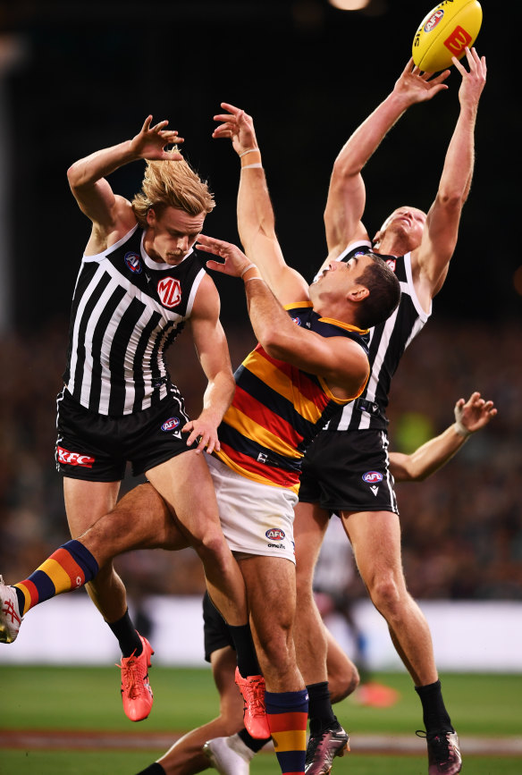 Tom Clurey of Port Adelaide marks behind Taylor Walker of the Crows and Miles Bergman of Port Adelaide.