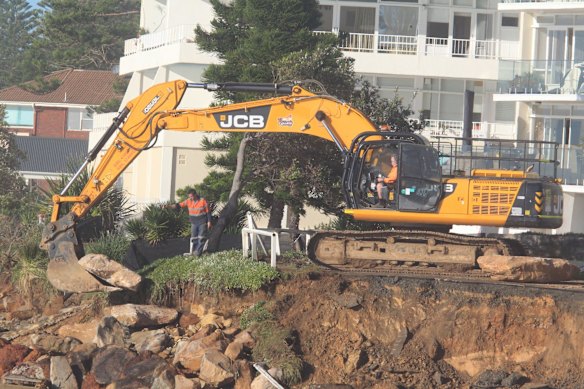 Massive boulders are lifted into place at Collaroy Beach this morning.