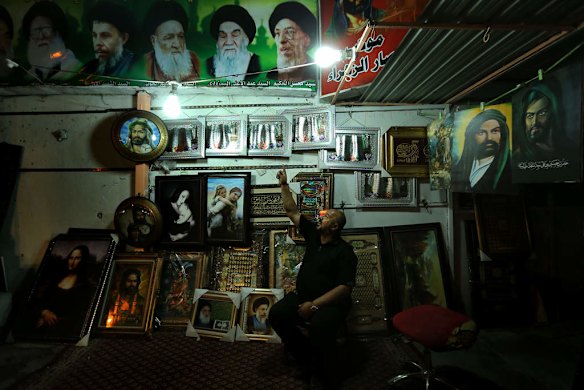 Mohammed Khadum sits among the many Shiite religious paintings and banners at his stall on Karada street in the Karada area of Baghdad.