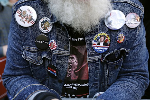 A demonstrator wears a shirt and buttons supporting President Donald Trump outside the Pennsylvania Convention Center where votes are being counted.