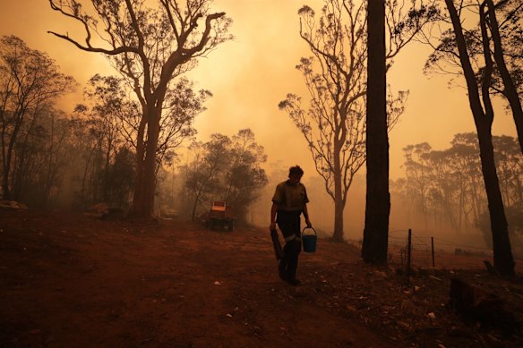 People defending their homes with pails as bushfire approaches Steveys Forest Road in Oakdale NSW on Friday 6 December 2019. 
