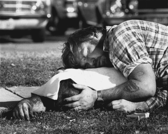 A man grieves over his brother, one of the dead.