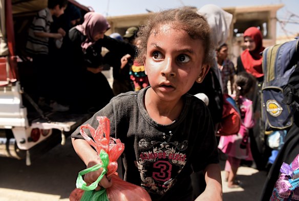 A girl in state of shock arrives with her family at a screening point.
