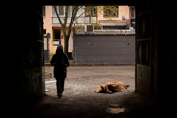 A man walks past the body of a civilian in the street after a Russian rocket hit a residential building in Kharkiv.